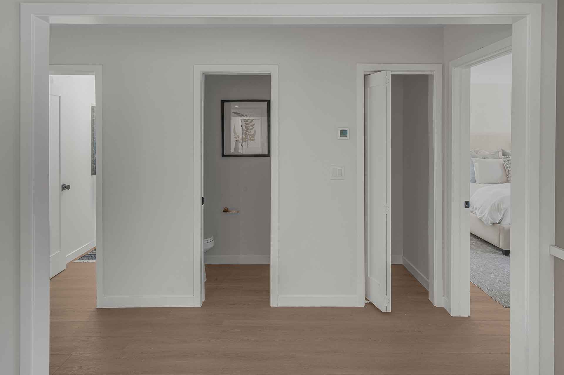 Modern Hallway with Wood Flooring and Multiple Doorways Leading to Bedrooms and Bathroom