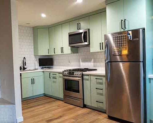 Full View of an ADU Kitchen with Sage Green Cabinets and Stainless Steel Appliances Full View of an ADU Kitchen with Sage Green Cabinets and Stainless Steel Appliances